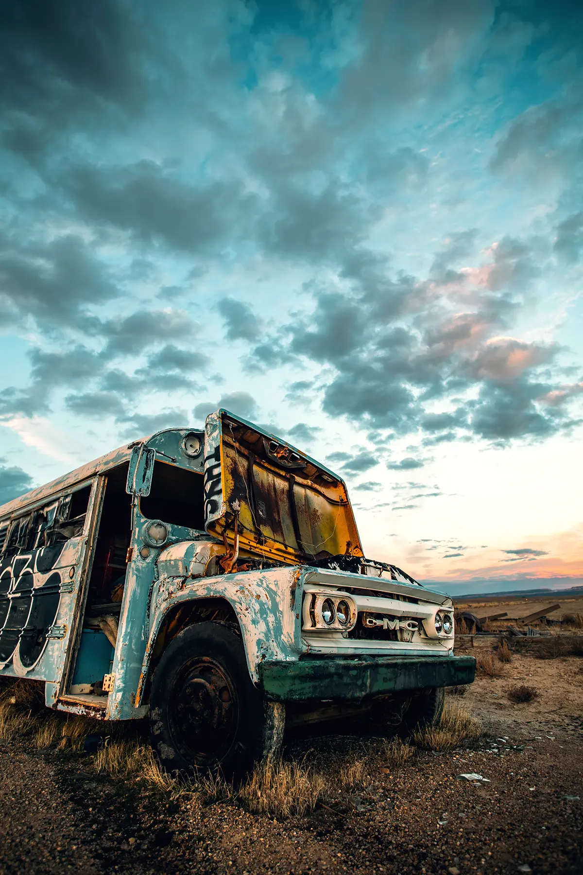 An old abandoned bus covered in graffiti in the desert.